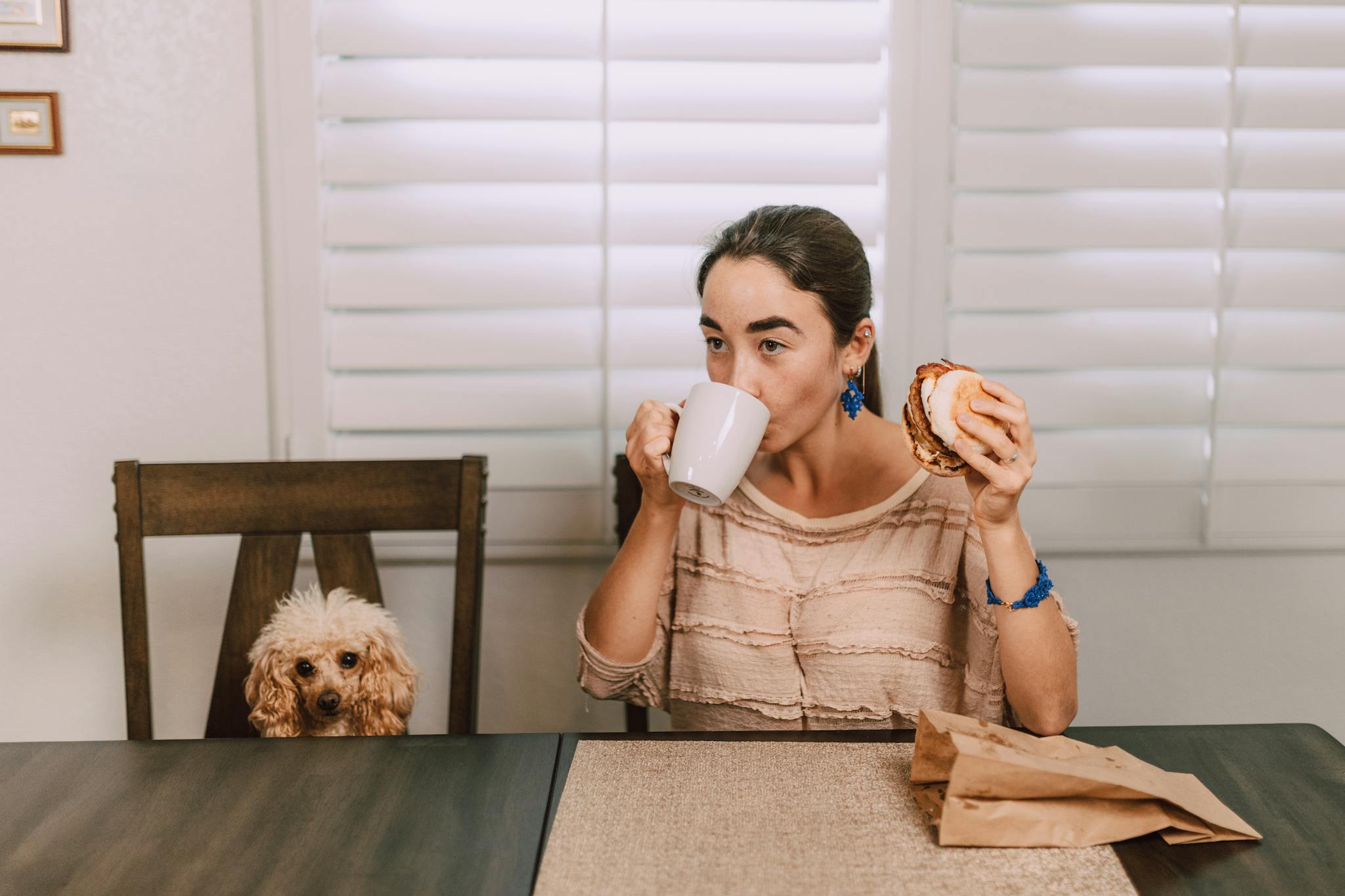 A woman sits indoors enjoying a cup of a pet-safe beverage